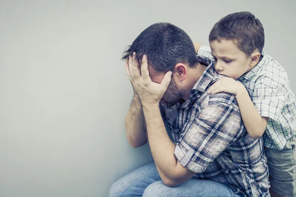 Triste hijo abrazando a su padre cerca de la pared — Foto de Stock