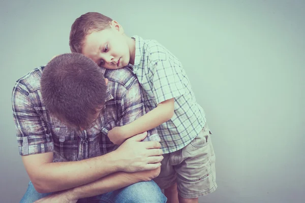 Sorgliga son kramar hans pappa nära vägg — Stockfoto