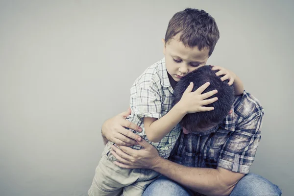 Sorgliga son kramar hans pappa nära vägg — Stockfoto