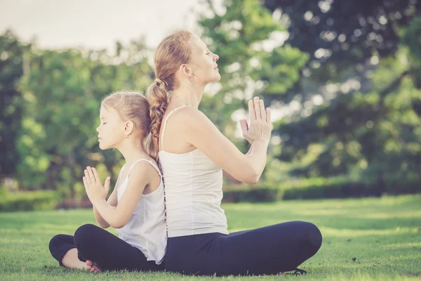 Mãe e filha fazendo exercícios de ioga na grama no parque . — Fotografia de Stock