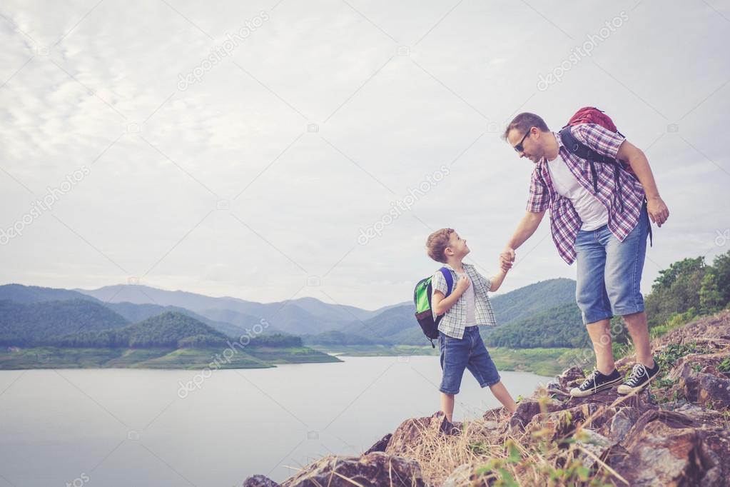 Father and son standing near the lake.