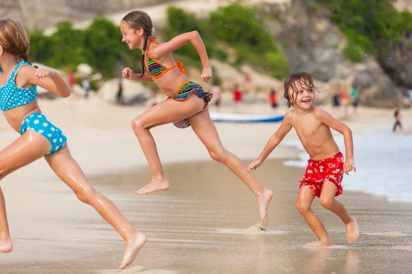 Tres niños felices jugando en la playa — Foto de Stock