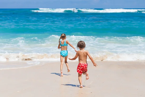 Hermana y hermano jugando en la playa durante el día . — Foto de Stock