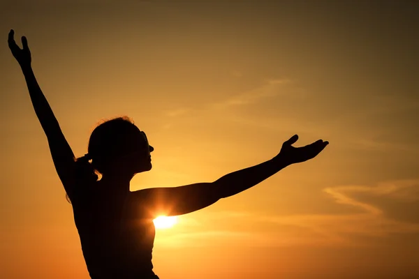 Vrouw open armen onder de zonsondergang op zee — Stockfoto