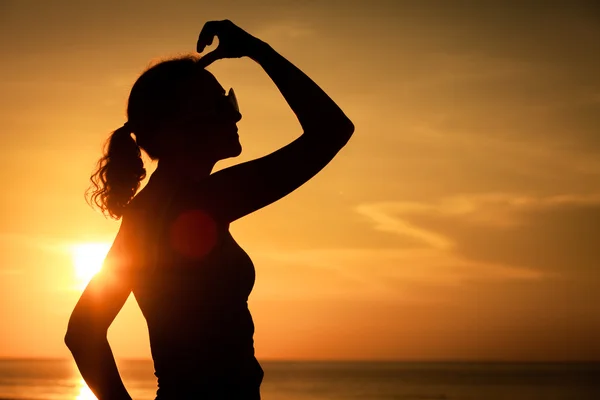 Frau mit offenen Armen unter dem Sonnenuntergang auf See — Stockfoto