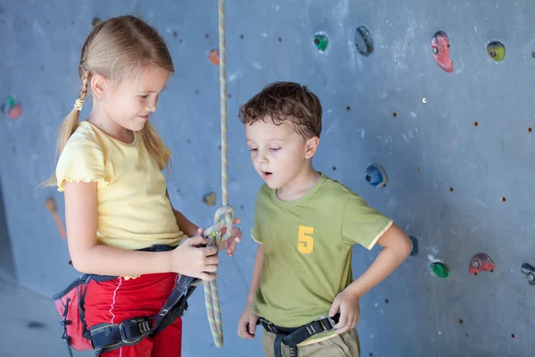 Brother and sister standing near a rock wall for climbing — Stock Photo, Image