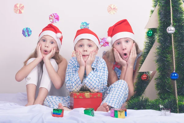 Glad lilla leende pojke och flickor med jul hatt. — Stockfoto