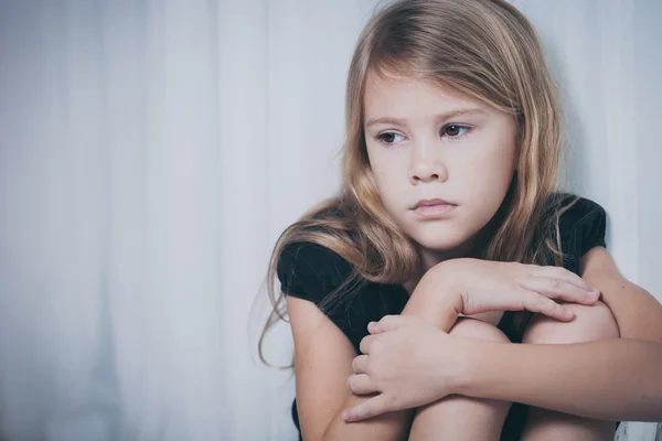 Портрет грустной маленькой девочки, сидящей у окна — стоковое фото