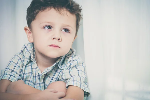 Porträtt av ledsen liten pojke sitter nära fönstret — Stockfoto