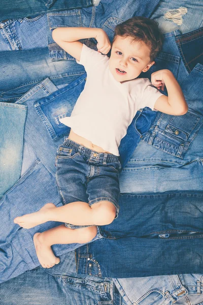 Cute little boy with sunglasses on the background jeans. — Stock Photo, Image