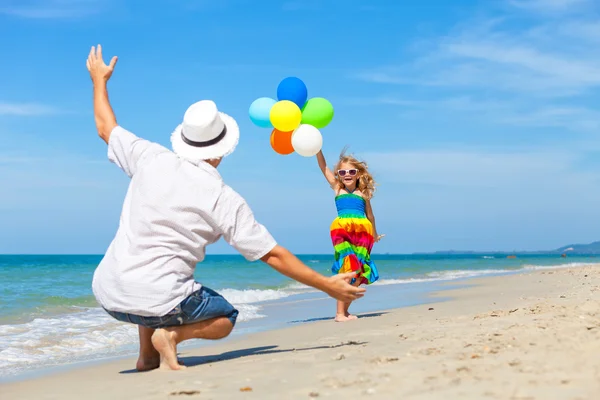 Vater und Tochter mit Luftballons spielen am Strand der da — Stockfoto