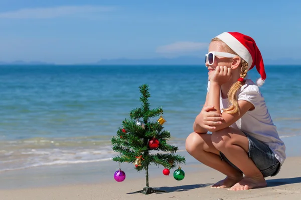 Boldog kis lány ül a strandon a nap idő. — Stock Fotó