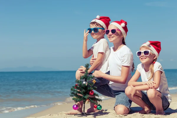 Trzy szczęśliwe dzieci bawiące się na plaży w czasie dnia. — Zdjęcie stockowe