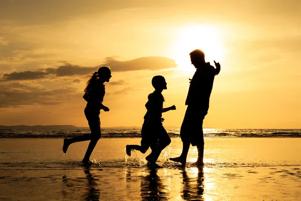 Vader en kinderen spelen op het strand op de zonsondergang keer. — Stockfoto