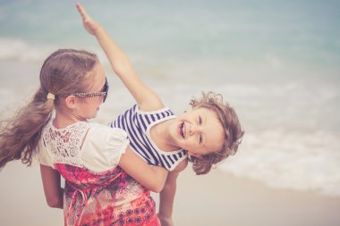 Kız ve erkek kardeş kumsalda gün anda oynamak.
