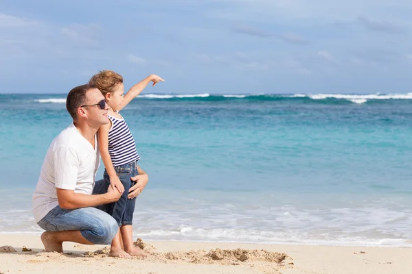 Feliz padre e hijo jugando en la playa durante el día . — Foto de Stock