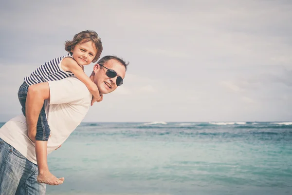 Feliz pai e filho brincando na praia na hora do dia . — Fotografia de Stock