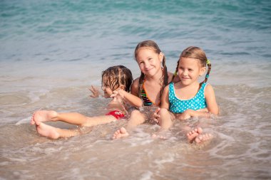 Üç mutlu çocuklar kumsalda oynarken