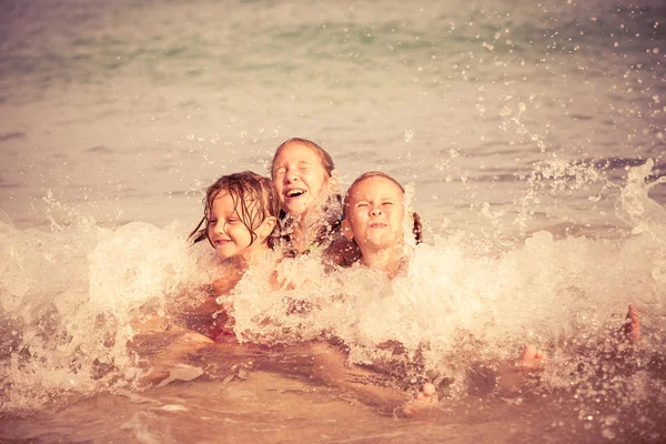 Trois enfants heureux jouant sur la plage — Photo