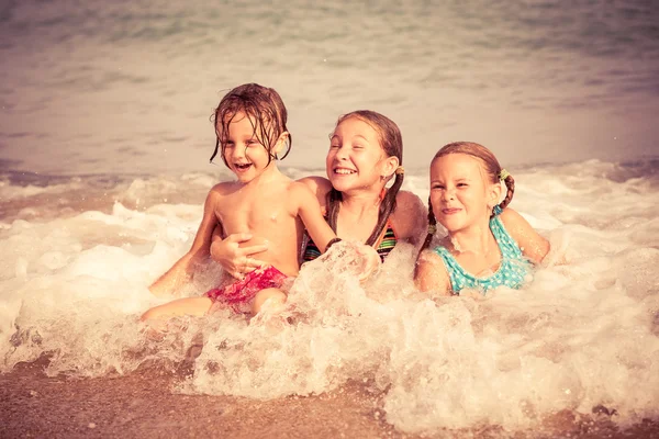 Tři šťastné děti si hrají na pláži — Stock fotografie