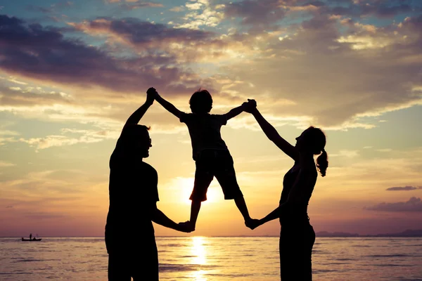 Silhouet van gelukkige familie die spelen op het strand bij de sunse — Stockfoto