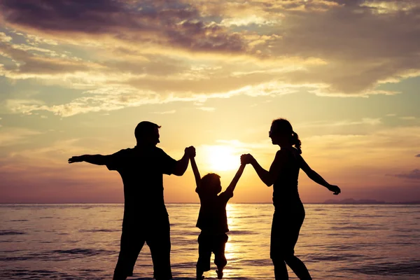 Silhouette einer glücklichen Familie, die am Strand in der Sonne spielt — Stockfoto