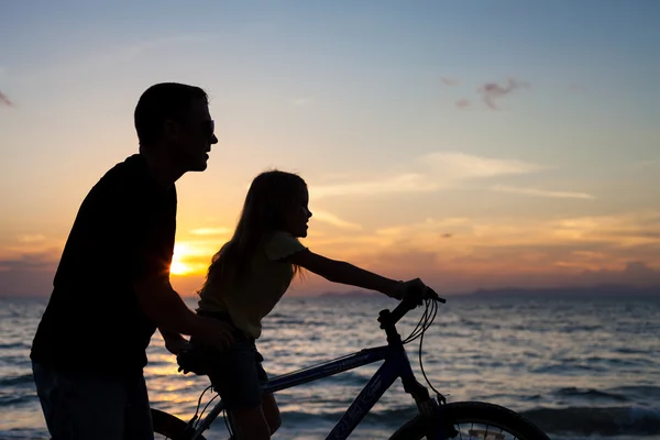 Vater und Tochter spielen am Strand bei Sonnenuntergang. — Stockfoto