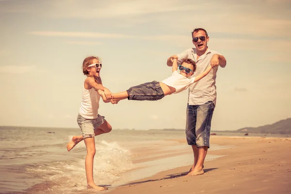 Pai e filhos brincando na praia no dia . — Fotografia de Stock