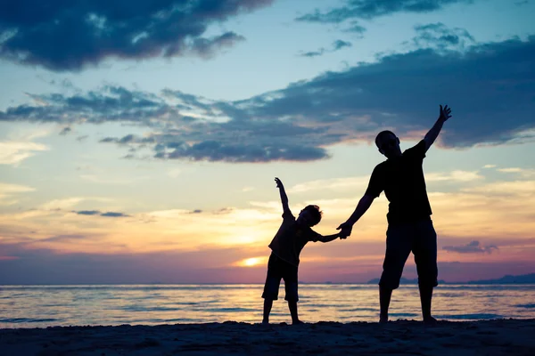 父亲和儿子在日落的时候在海滩上玩. — 图库照片