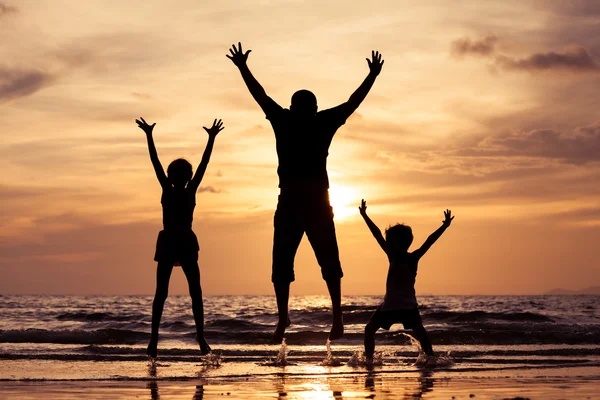 Padre e figli che giocano in spiaggia al tramonto . — Foto Stock