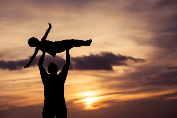 Père et fils jouant sur la plage au coucher du soleil . — Photo