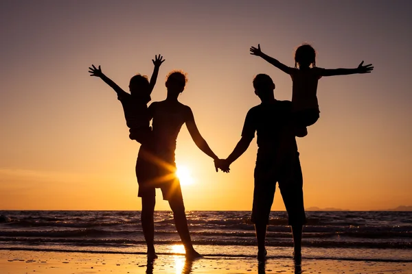 Silhouette einer glücklichen Familie, die am Strand in der Sonne spielt — Stockfoto