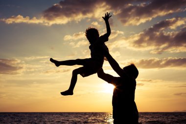 Baba ve oğul sahilde günbatımı anda oynamak.