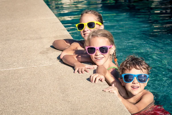 Crianças felizes brincando na piscina durante o dia — Fotografia de Stock