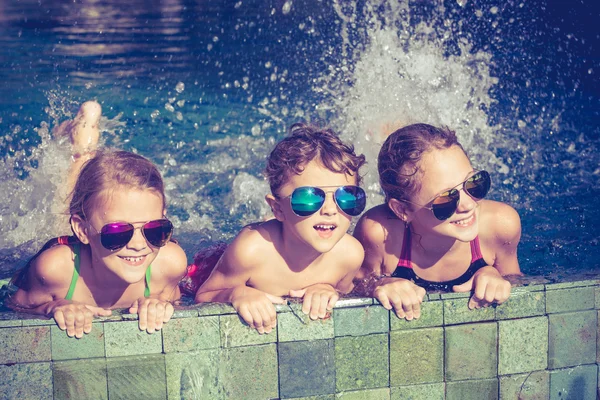 Niños felices jugando en la piscina durante el día — Foto de Stock