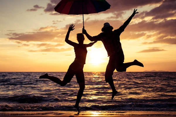 Glückliche Familie springt am Strand bei Sonnenuntergang. — Stockfoto