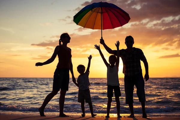 Silhouette einer glücklichen Familie, die am Strand in der Sonne spielt — Stockfoto