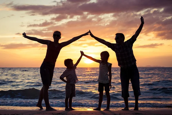 Silueta de familia feliz que juega en la playa al atardecer —  Fotos de Stock