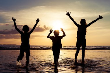 Mutlu çocuk sahilde günbatımı anda oynamak.