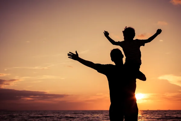 Pai e filho brincando na praia na hora do pôr do sol . — Fotografia de Stock