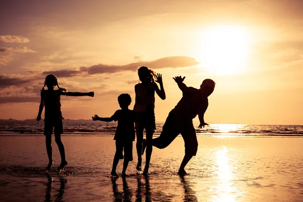 Pai e crianças brincando na praia na hora do pôr do sol . — Fotografia de Stock