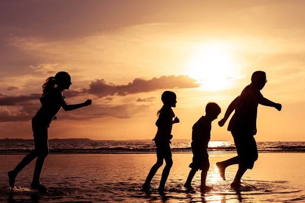 Père et enfants jouant sur la plage au coucher du soleil . — Photo