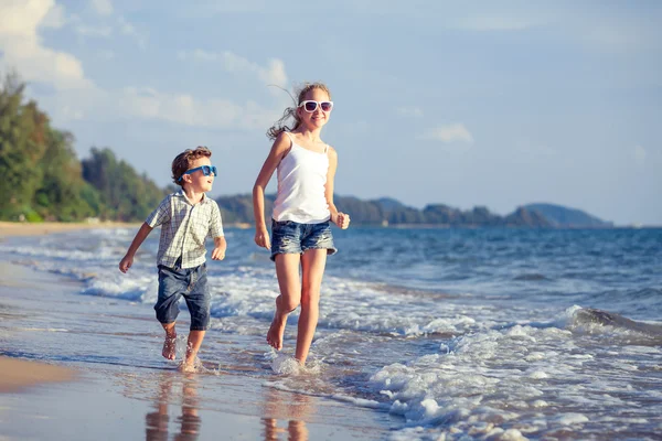 Niños felices jugando en la playa durante el día . — Foto de Stock