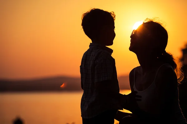 Mutter und Sohn spielen am Strand bei Sonnenuntergang. — Stockfoto