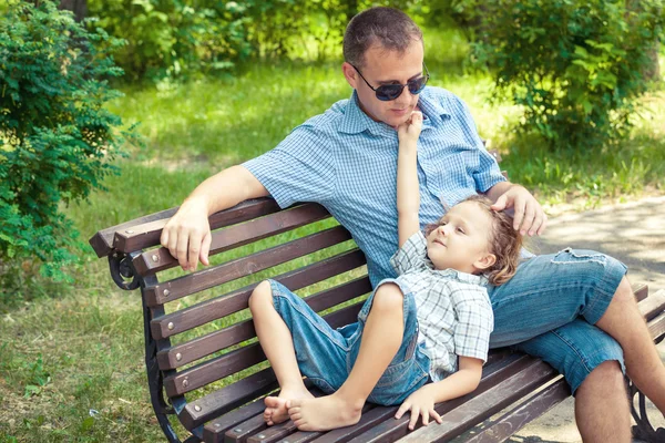 Otec a syn hraje v parku na lavičce v denní době. — Stock fotografie