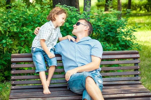 Far och son började spela i parken på bänk med dagen. — Stockfoto