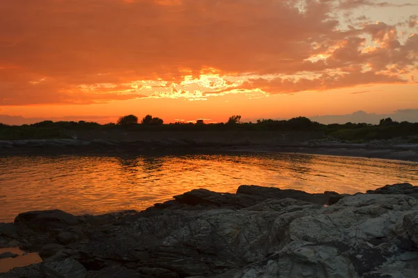 Puesta de sol en una costa rocosa . — Foto de Stock