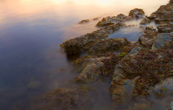 Tramonto su una riva rocciosa . — Foto Stock