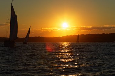 Gün batımında yelkenli tekneler.