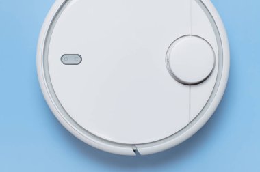 Mavi arka planda modern robot elektrikli süpürge düz yerde yatıyordu. Yeni teknolojiler, hızlı ev temizliği, otomatik robot asistanı. Rahatlamak için boş zaman. Gelecek teknolojisi, temizlik için akıllı aygıt.